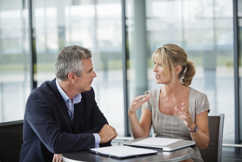 Seated male receiving leadership coaching for scientists from a woman in business attire